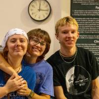 3 people with all smiles as they watch the event